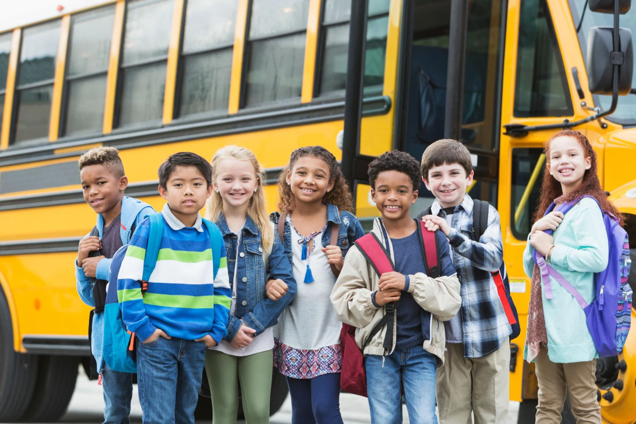 Students standing together near a school bus representing school scheduling flexibility